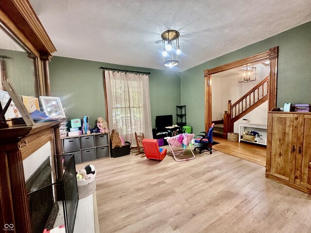 211 6th St, Covington, IN 47932 - living room featuring wood finished floors, a textured ceiling, and stairs