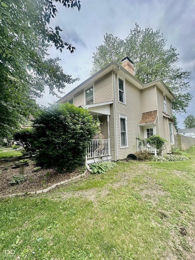 211 6th St, Covington, IN 47932 - view of side of property with a chimney, a lawn, and a porch