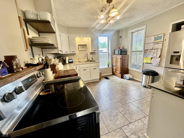 211 6th St, Covington, IN 47932 - kitchen featuring electric range, black microwave, a textured ceiling, white fridge with ice dispenser, and white cabinets
