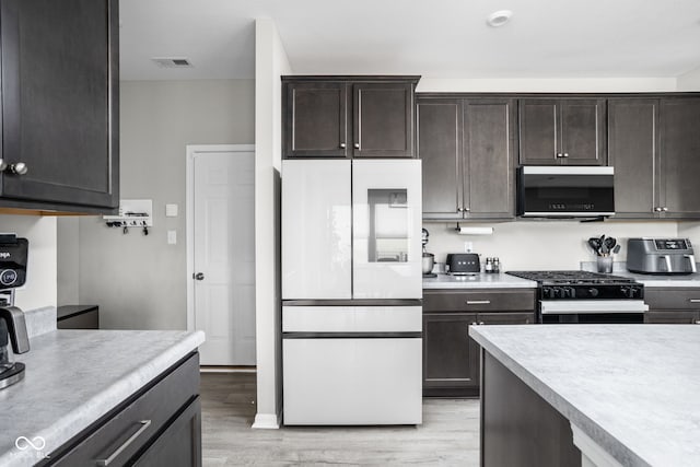 6305 N Woodhaven Dr, Mccordsville, IN 46055 - kitchen featuring white refrigerator, black range with gas stovetop, light countertops, and light wood finished floors