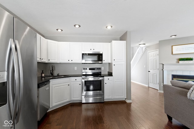603 Daviess Dr, Westfield, IN 46074 - kitchen featuring stainless steel appliances, a sink, dark countertops, dark wood-type flooring, and recessed lighting