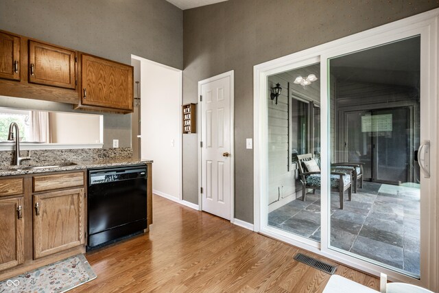 8223 Thoroughbred Run, Indianapolis, IN 46256 - kitchen featuring dishwasher, a sink, a high ceiling, light wood-type flooring, and brown cabinetry
