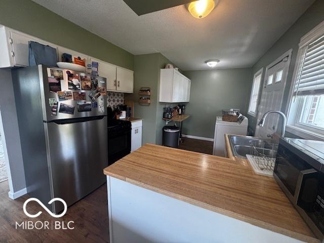 1820 Martin St, Indianapolis, IN 46237 - kitchen with stainless steel appliances, a sink, white cabinetry, washer and dryer, and dark wood-style floors