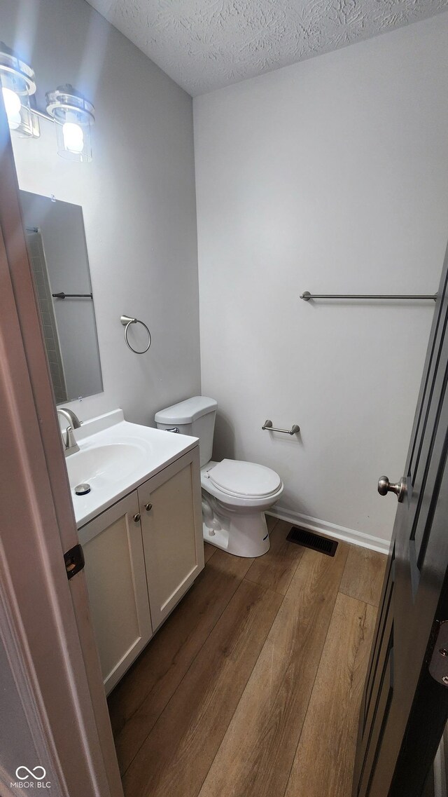 1836 Queensbridge Cir, Indianapolis, IN 46219 - half bath featuring wood finished floors, toilet, vanity, and a textured ceiling