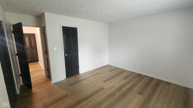 1836 Queensbridge Cir, Indianapolis, IN 46219 - unfurnished bedroom with wood finished floors, a textured ceiling, and baseboards