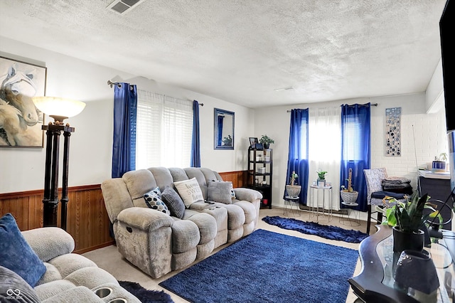 2832 Hillside Ave, Indianapolis, IN 46218 - living room with healthy amount of natural light, a textured ceiling, carpet flooring, wood walls, and a wainscoted wall