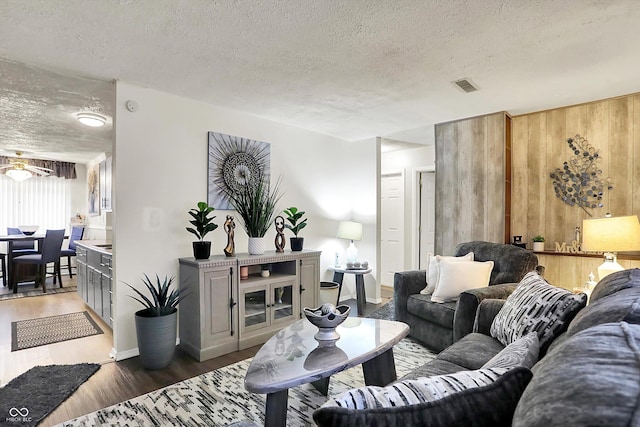 2832 Hillside Ave, Indianapolis, IN 46218 - living room featuring a textured ceiling, wood finished floors, wood walls, and baseboards