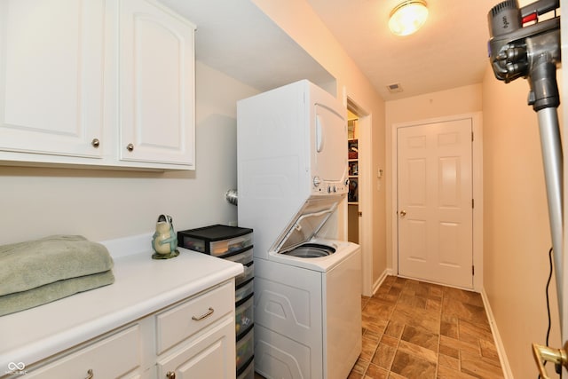 2805 Rylee Ct, Greenwood, IN 46143 - washroom with stacked washer and clothes dryer, cabinet space, baseboards, and stone finish floors