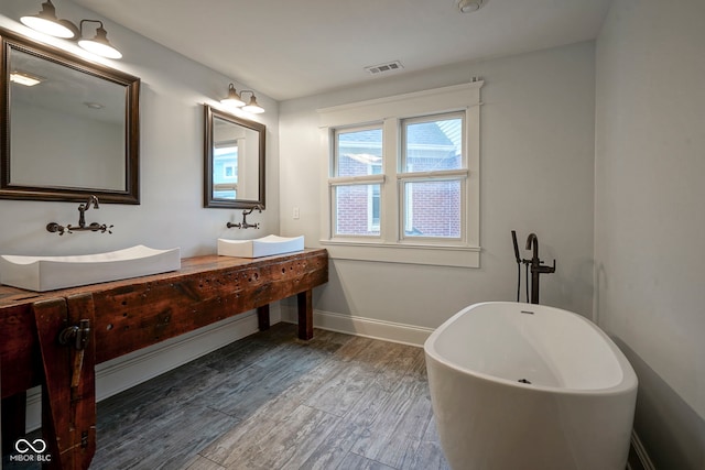1512 Bellefontaine St, Indianapolis, IN 46202 - bathroom with a freestanding bath, wood finished floors, double vanity, and baseboards