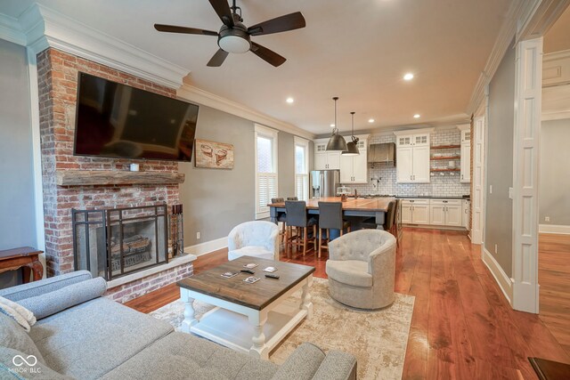 1512 Bellefontaine St, Indianapolis, IN 46202 - living room with baseboards, wood finished floors, ceiling fan, a fireplace, and ornamental molding