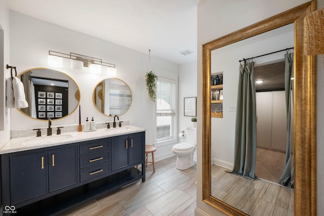 22 N Bolton Ave, Indianapolis, IN 46219 - full bathroom with double vanity, toilet, baseboards, a shower with shower curtain, and wood finish floors