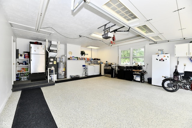 1910 Ivy Dr, Anderson, IN 46011 - garage featuring freestanding refrigerator, gas water heater, a garage door opener, and washer and dryer