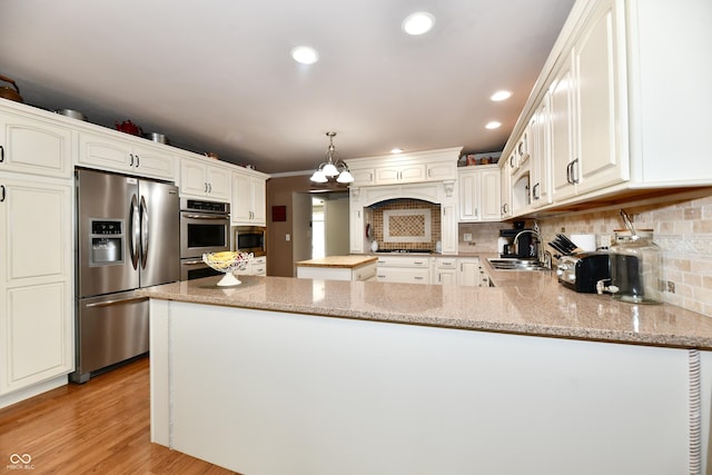1910 Ivy Dr, Anderson, IN 46011 - kitchen featuring stainless steel appliances, a sink, a peninsula, light stone countertops, and backsplash
