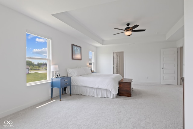 bedroom featuring a raised ceiling, carpet flooring, baseboards, and a ceiling fan