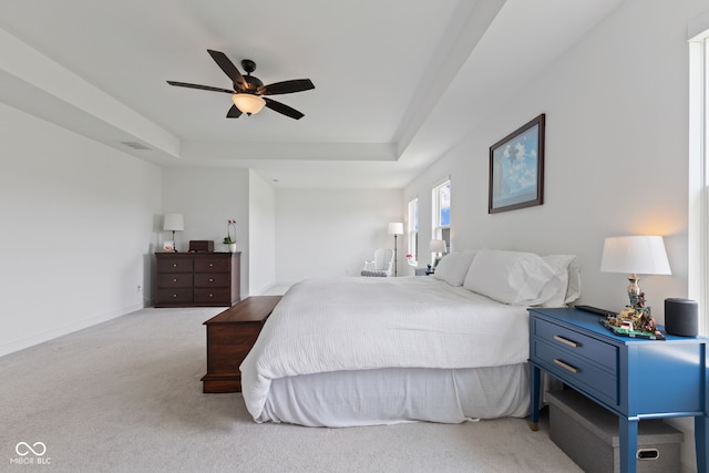 carpeted bedroom featuring a raised ceiling, ceiling fan, and baseboards
