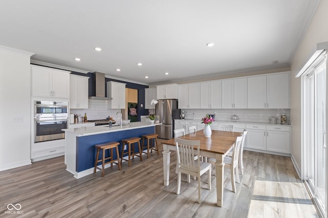 dining space with crown molding, light wood-style flooring, recessed lighting, and baseboards