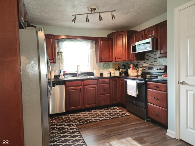 7870 E County Road 150 S, Avon, IN 46123 - kitchen with appliances with stainless steel finishes, dark countertops, dark wood-style flooring, rail lighting, and backsplash
