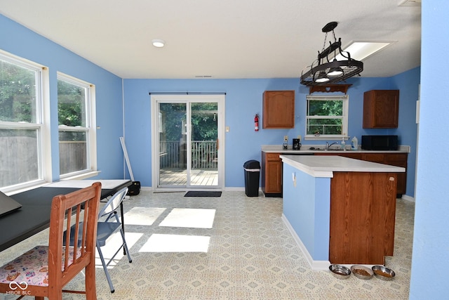 9237 Ogden Dunes Ct, Camby, IN 46113 - kitchen featuring light countertops, healthy amount of natural light, brown cabinets, and black microwave