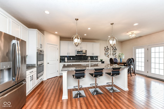 15097 Thoroughbred Dr, Fishers, IN 46040 - kitchen with stainless steel appliances, dark wood-style floors, tasteful backsplash, a kitchen breakfast bar, and recessed lighting