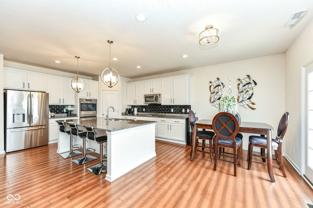 15097 Thoroughbred Dr, Fishers, IN 46040 - kitchen featuring stainless steel appliances, tasteful backsplash, a kitchen bar, recessed lighting, and an island with sink