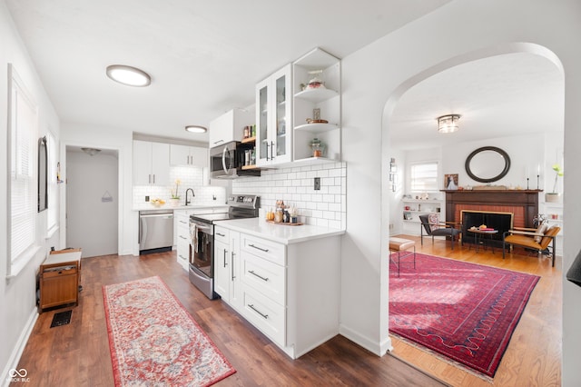 6640 E Washington St, Indianapolis, IN 46219 - kitchen featuring appliances with stainless steel finishes, arched walkways, a sink, backsplash, and light countertops