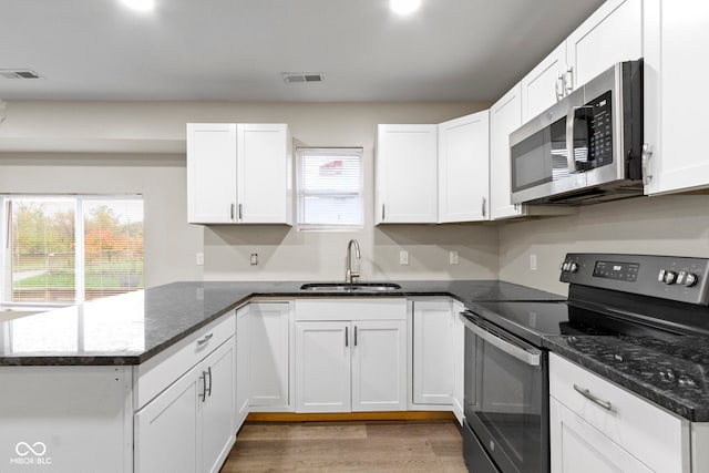 802 N Tuxedo St, Indianapolis, IN 46201 - kitchen featuring appliances with stainless steel finishes, a sink, a peninsula, and white cabinetry