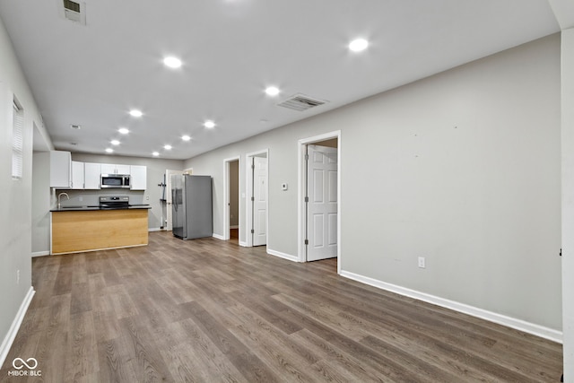 802 N Tuxedo St, Indianapolis, IN 46201 - unfurnished living room with dark wood-style floors, a sink, baseboards, and recessed lighting