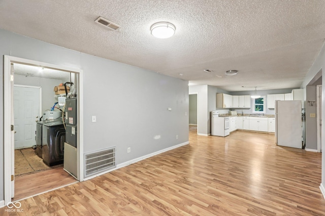 2640 S Silcox Rd, Paragon, IN 46166 - unfurnished living room featuring light wood finished floors, a textured ceiling, and washer / clothes dryer