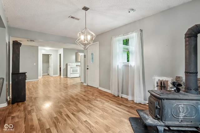 2640 S Silcox Rd, Paragon, IN 46166 - dining space featuring a wood stove, light wood-style floors, a textured ceiling, and a chandelier
