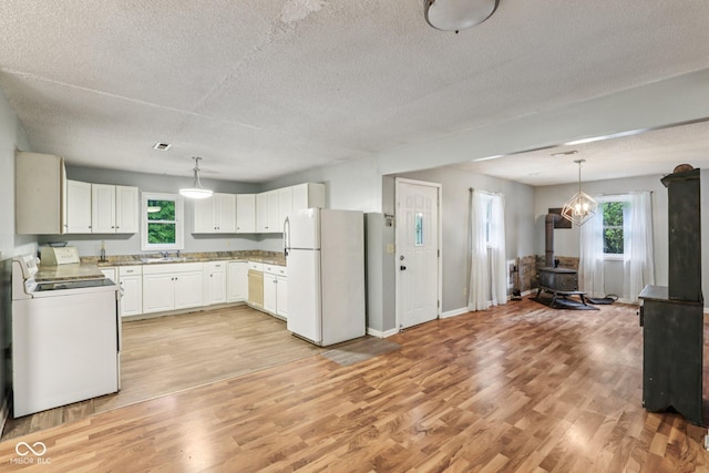 2640 S Silcox Rd, Paragon, IN 46166 - kitchen with white appliances, a wood stove, healthy amount of natural light, light wood-style floors, and a textured ceiling