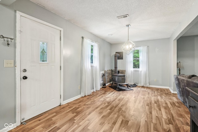 2640 S Silcox Rd, Paragon, IN 46166 - foyer entrance with light wood-type flooring, plenty of natural light, a wood stove, and a textured ceiling
