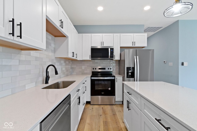 8355 Fieldfare Way, Indianapolis, IN 46237 - kitchen with stainless steel appliances, a sink, light wood finished floors, white cabinets, and tasteful backsplash