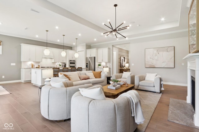 12594 Pasco St, Fishers, IN 46038 - living area featuring a chandelier, crown molding, wood finished floors, a fireplace with flush hearth, and baseboards