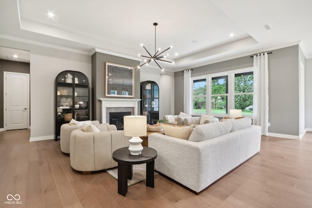 12594 Pasco St, Fishers, IN 46038 - living room with a tray ceiling, light wood-style floors, a glass covered fireplace, baseboards, and recessed lighting