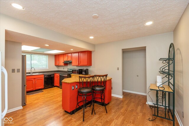 4965 Hawthorne Way, Avon, IN 46123 - kitchen with stainless steel appliances, a textured ceiling, light wood-type flooring, under cabinet range hood, and a breakfast bar area