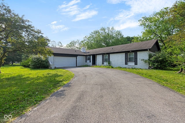 3141 Citadel Ct, Indianapolis, IN 46268 - view of front of home with brick siding, an attached garage, asphalt driveway, a front lawn, and a chimney