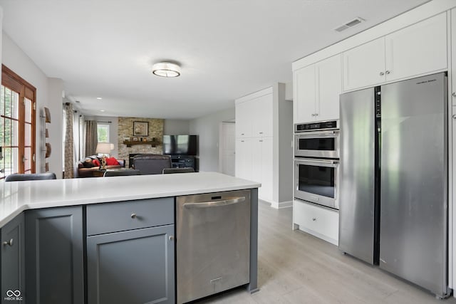10410 Trillium Ct, Noblesville, IN 46060 - kitchen featuring appliances with stainless steel finishes, gray cabinets, light wood-type flooring, open floor plan, and light countertops