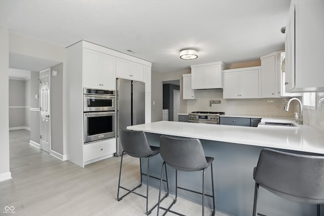 10410 Trillium Ct, Noblesville, IN 46060 - kitchen with appliances with stainless steel finishes, a peninsula, a sink, tasteful backsplash, and light wood-style floors