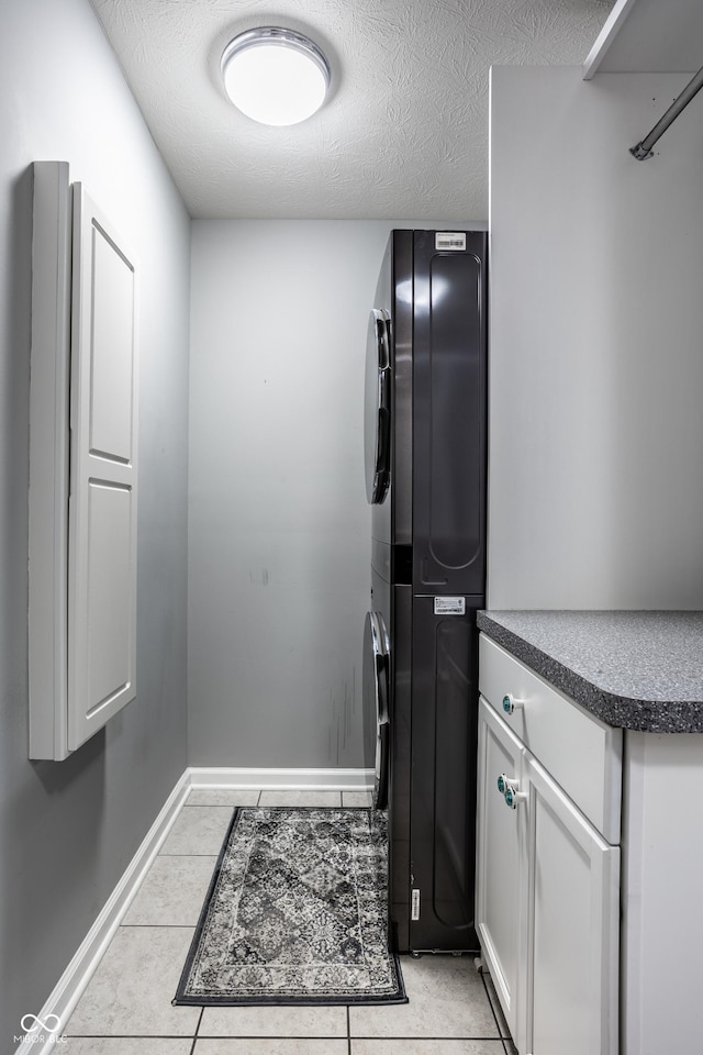 478 Firefly Ln, Carmel, IN 46032 - laundry area with stacked washing machine and dryer, cabinet space, light tile patterned floors, baseboards, and a textured ceiling
