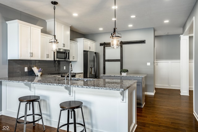478 Firefly Ln, Carmel, IN 46032 - kitchen featuring appliances with stainless steel finishes, a peninsula, a sink, decorative backsplash, and a barn door