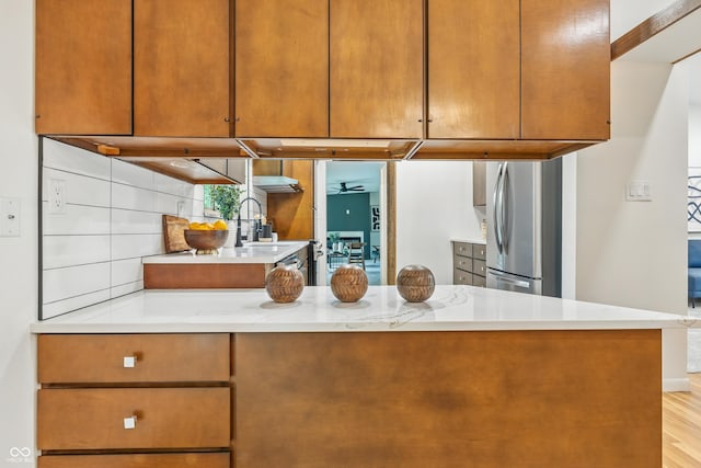 6704 Hoover Rd, Indianapolis, IN 46260 - kitchen featuring freestanding refrigerator, light countertops, light wood finished floors, a sink, and a peninsula