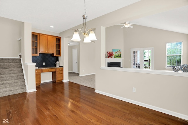 13528 Cuppertino Ln, Carmel, IN 46074 - kitchen featuring built in desk, brown cabinets, dark wood-style floors, glass insert cabinets, and vaulted ceiling