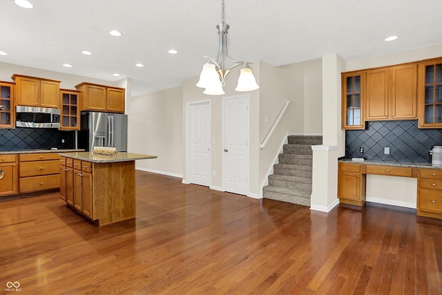 13528 Cuppertino Ln, Carmel, IN 46074 - kitchen featuring stainless steel appliances, brown cabinetry, recessed lighting, decorative backsplash, and glass insert cabinets