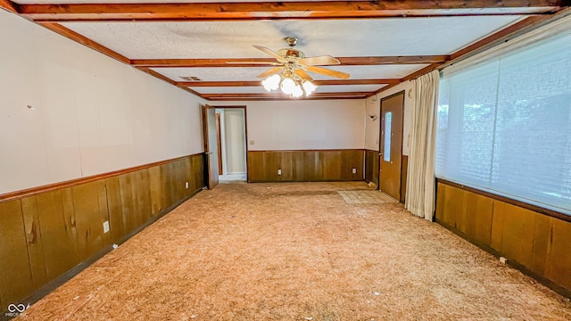 3215 E 10th St, Anderson, IN 46012 - spare room featuring wooden walls, a wainscoted wall, ceiling fan, beam ceiling, and carpet floors