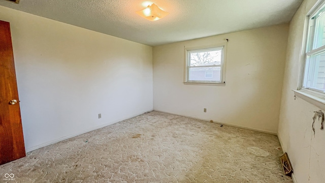 3215 E 10th St, Anderson, IN 46012 - empty room featuring plenty of natural light, carpet floors, and a textured ceiling