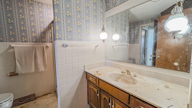 3215 E 10th St, Anderson, IN 46012 - bathroom with vanity, a wainscoted wall, wallpapered walls, tile walls, and toilet