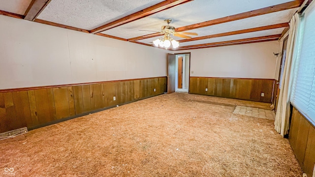 3215 E 10th St, Anderson, IN 46012 - spare room featuring a wainscoted wall, carpet floors, wood walls, beamed ceiling, and ceiling fan
