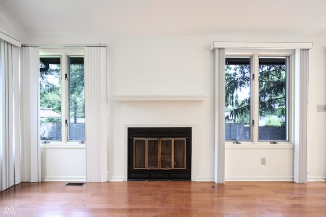 4462 Carya Sq, Columbus, IN 47201 - unfurnished living room with wood finished floors, healthy amount of natural light, and a glass covered fireplace