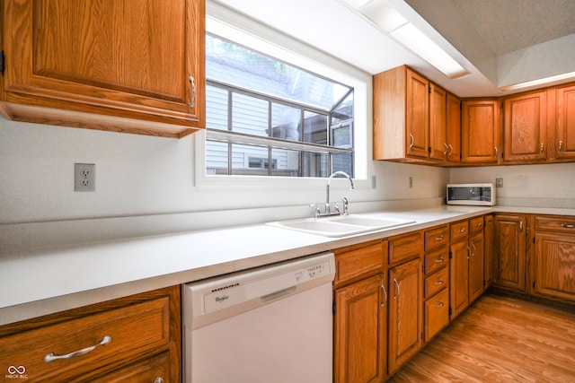 4462 Carya Sq, Columbus, IN 47201 - kitchen with white appliances, a sink, brown cabinetry, light wood-style flooring, and light countertops