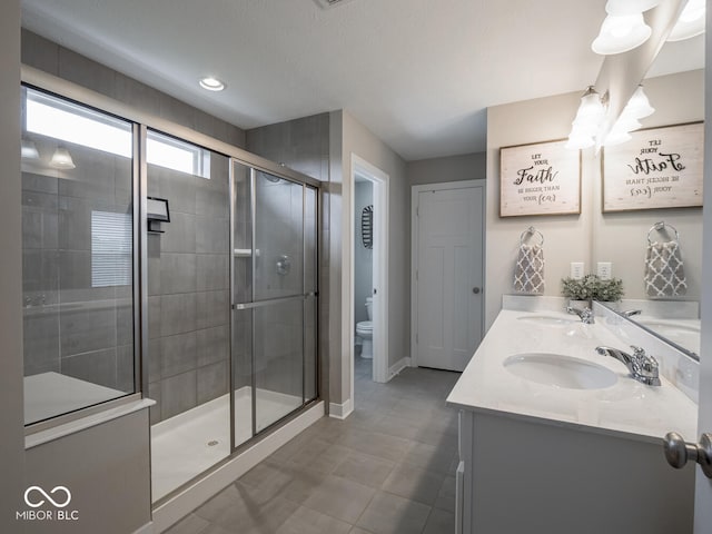 5684 Autumn Trl, Brownsburg, IN 46112 - bathroom featuring double vanity, toilet, a stall shower, baseboards, and tile patterned floors